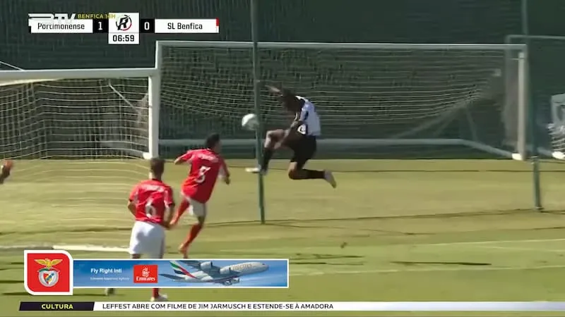 A youth football match with a lower-third banner ad below the action